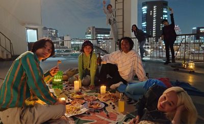 Изображение группы людей, устраивающих пикник на крыше города ночью