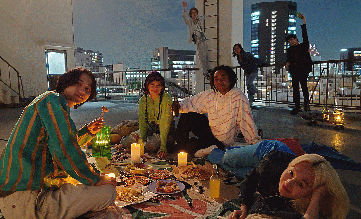 Image of a group of people having a picnic on a city rooftop at night