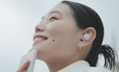 一個人佩戴入耳式耳機從手機聽音樂的特寫圖片