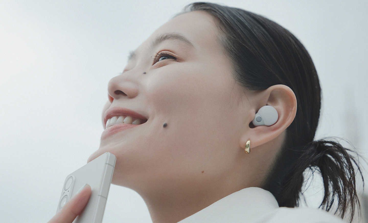 Close up image of a person listening to music on their phone via some in-ear headphones