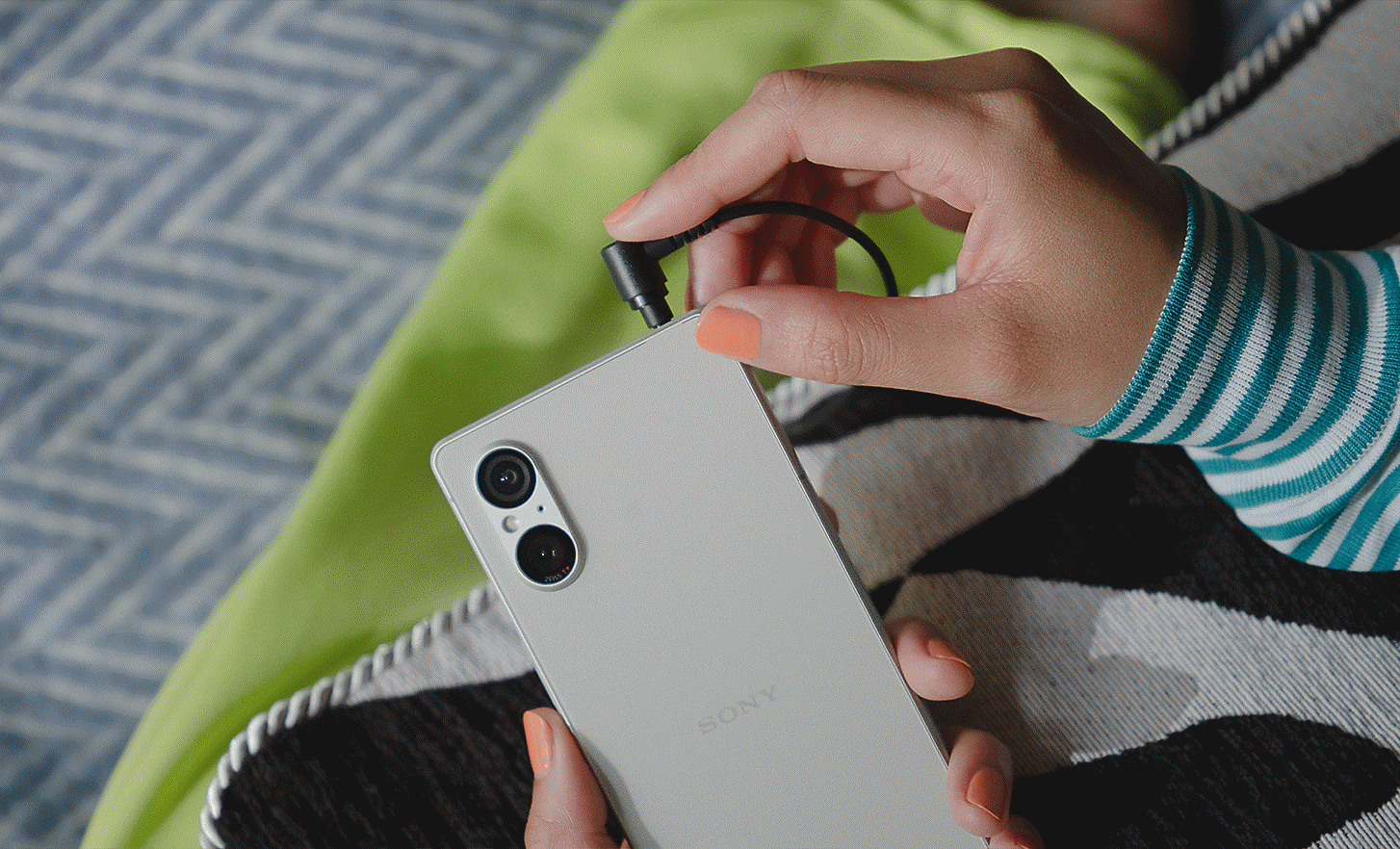 Close up image of a person plugging a cable into the Xperia 5 V headphone jack