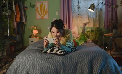 Изображение человека, лежащего на кровати и смотрящего видео на своем Xperia 5 V.