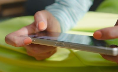 一個人在 Xperia 5 V 上玩遊戲，同時手指懸停在快門按鈕上的特寫圖片