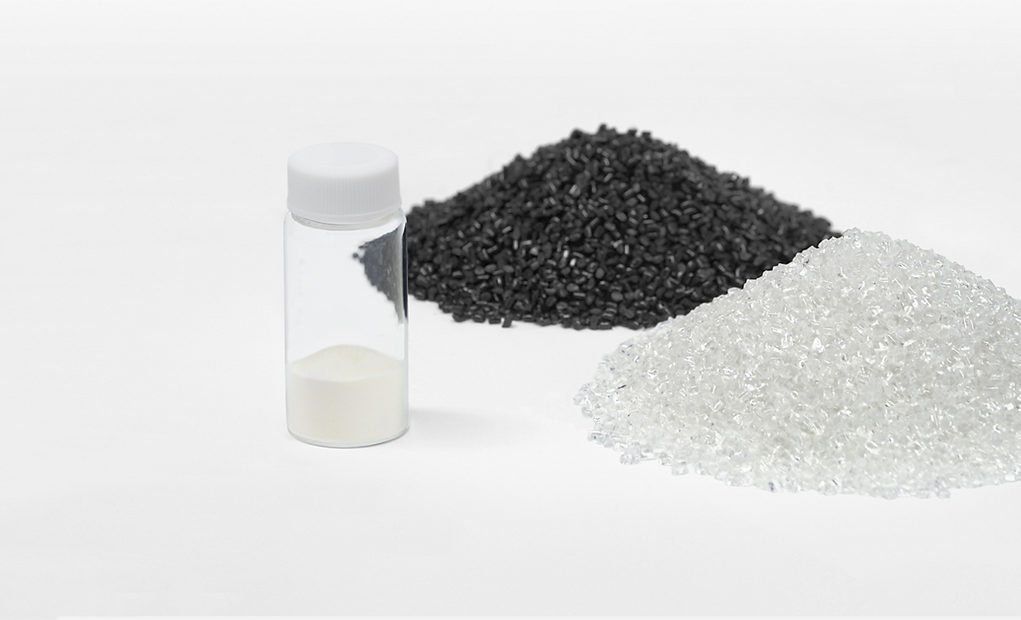 Image of piles of black and silver plastic granules next to a tube of powder