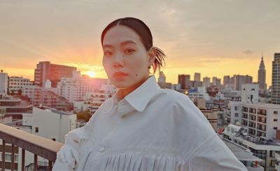 Image of a person on a rooftop with a sun setting over a city skyline in the background