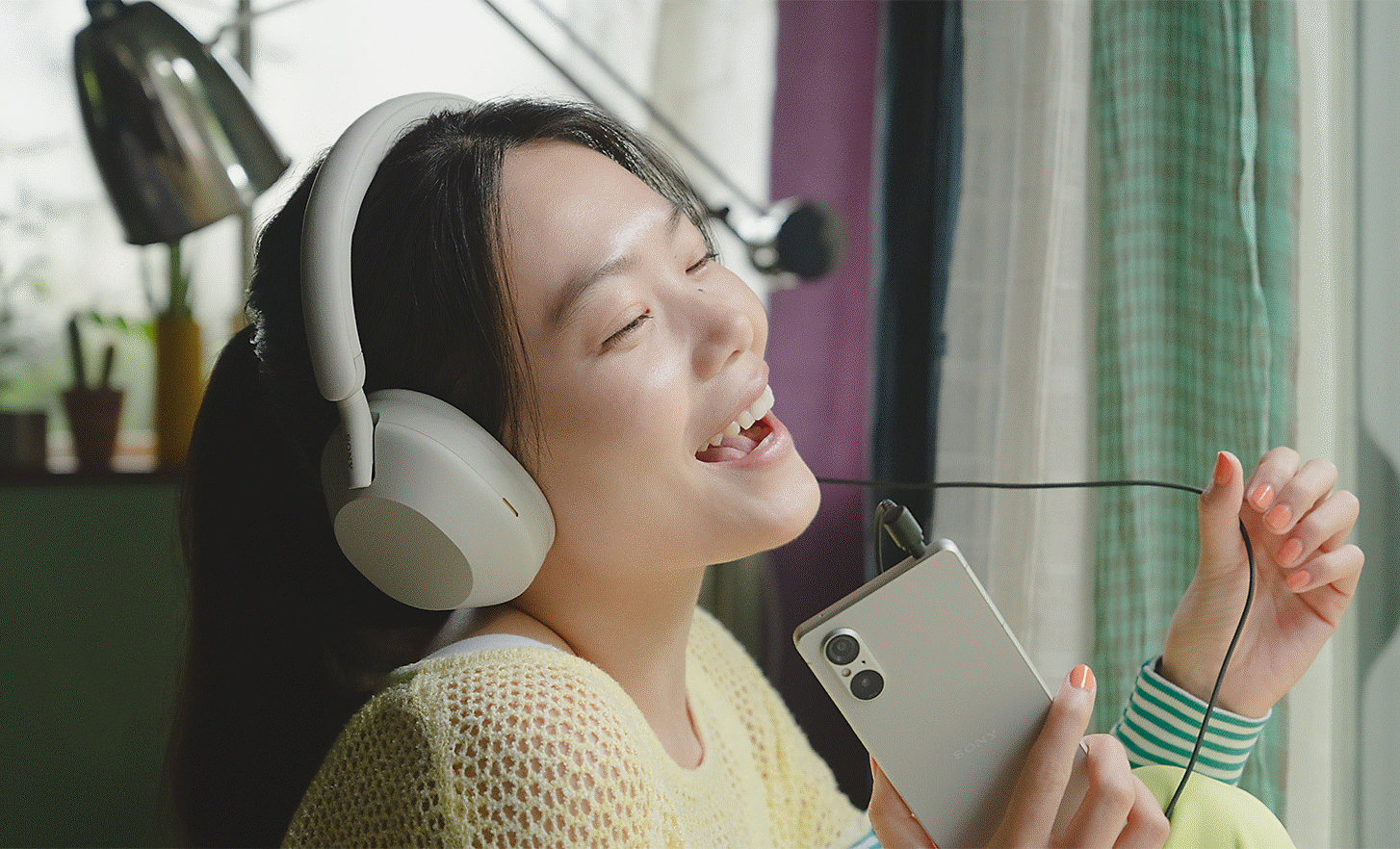 Image d'une personne écoutant le son diffusé par un Xperia 5 V avec un casque blanc et chantant en chœur avec la musique