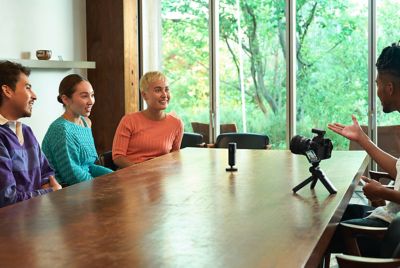 Image montrant un microphone placé au centre d'une table, entouré de quatre personnes en train de converser