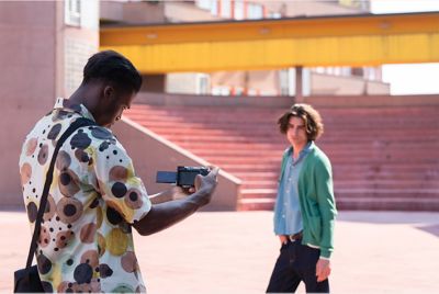 Imagen de un hombre sosteniendo la cámara para filmar a otro hombre al aire libre