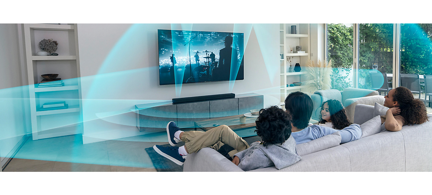 Familie auf einem Sofa, die einen Fernseher mit einer Soundbar auf einem Marmorschrank ansieht