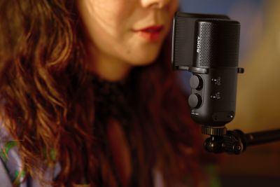 Hình ảnh sử dụng thể hiện một phụ nữ đang hát vào micro đặt gần miệng của cô, micro này có gắn màng lọc âm