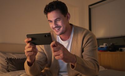 A person sat down in an indoor setting using their Xperia 5 V to watch a video 