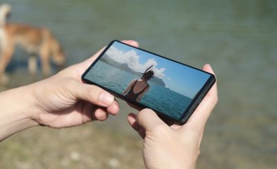 Una persona che porta a spasso il cane mentre guarda contenuti sull'Xperia 1 VI.