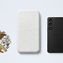 Uma seleção de materiais brutos reutilizáveis junto com a embalagem da Sony e o revestimento externo de um smartphone.