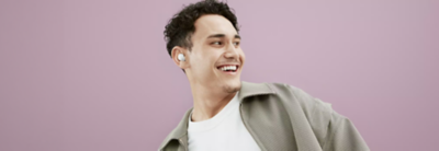 Billede af en person, der kigger til højre og griner, mens vedkommende bærer et hvidt par LinkBuds S-øretelefoner