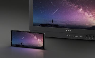 Изображение телевизора BRAVIA с изображением звездного неба на экране и телефона перед телевизором, показывающего то же звездное небо