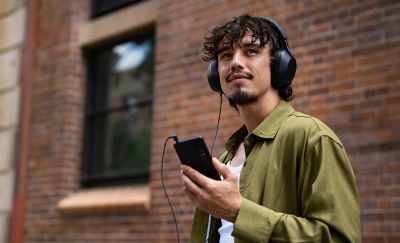persona escuchando música con auriculares conectados al teléfono mediante un cable