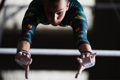 Imagen de ejemplo de una gimnasta en pleno balanceo entre barras asimétricas, con los brazos extendidos