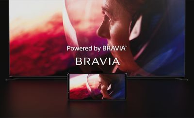 螢幕顯示「Powered by BRAVIA」和 BRAVIA 標誌的特寫，前方有一支手機