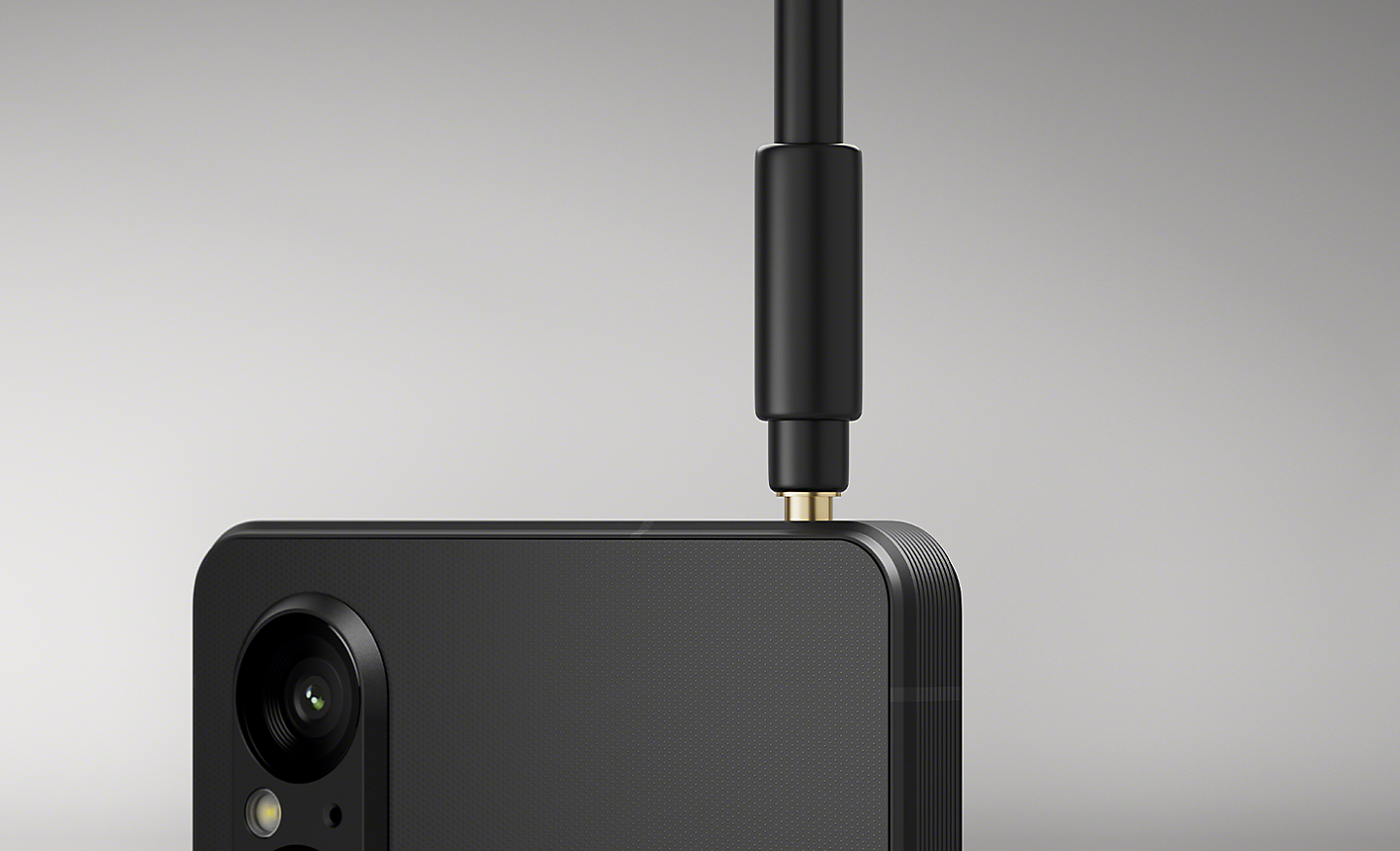 近拍影像裡一條耳機線連到 Xperia 1 V 的 3.5 mm 音訊插孔