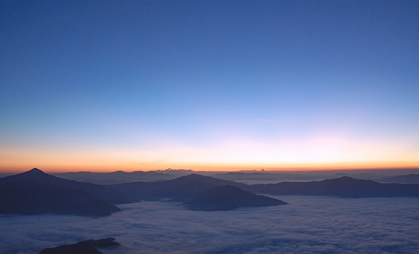 Spectacular view over distant mountains swathed in low cloud at daybreak