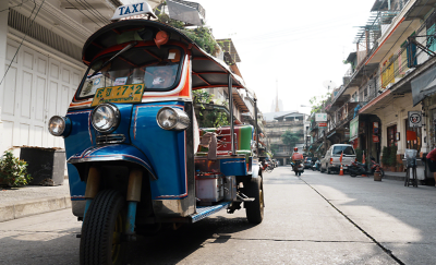 Um tuk tuk motorizado sendo conduzido ao longo de uma rua da cidade