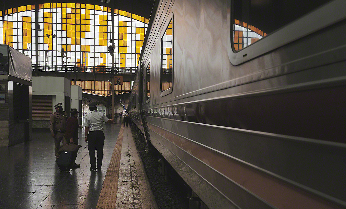 大型火車站中，一些在月台上站在列車旁的人