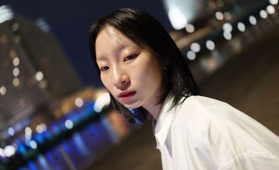 Close up of a person shot at an angle during the night with a blurry city background