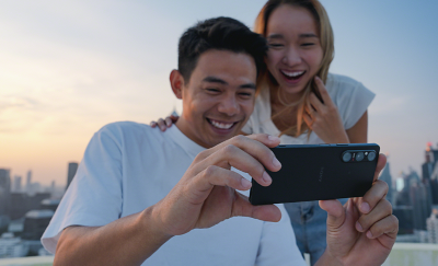Двое молодых людей наслаждаются просмотром контента на улице на Xperia 1 V.
