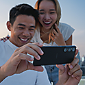 Δύο νέοι που απολαμβάνουν την παρακολούθηση περιεχομένου σε εξωτερικό χώρο σε ένα Xperia 1 V