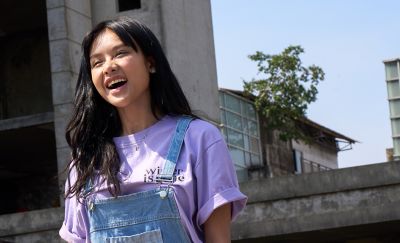 Sunlit portrait of a young woman against an urban backdrop