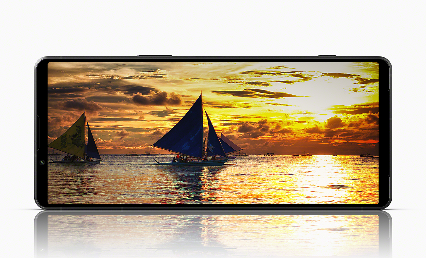 Telefon Xperia 1 V v ležečem položaju kaže sliko ladij, ki plujejo po morju ob spektakularnem sončnem zahodu