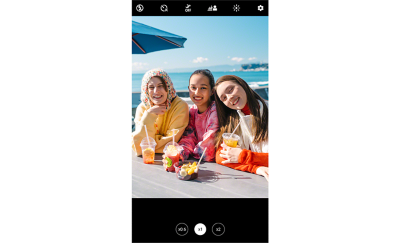 Ảnh chụp màn hình cho thấy hình ảnh ba phụ nữ trẻ đang cười trước camera, ngồi bên một chiếc bàn nhìn ra biển
