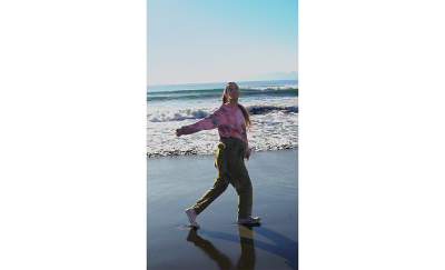 Молодая женщина гуляет по пляжу и улыбается в камеру