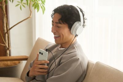 Una persona sentada en un sofá con auriculares utilizando un smartphone Xperia 10 VIII
