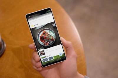 Una mano sostiene un smartphone Xperia 10 VIII que muestra una cuenta de redes sociales con una foto de comida