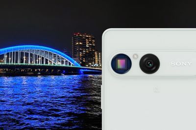 Primer plano del sensor de la cámara del smartphone Sony Xperia 10 VIII con una foto nocturna de un puente iluminado de azul de fondo