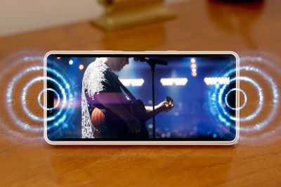Smartphone Xperia 10 VIII reproduciendo el vídeo de un concierto en directo con brillantes ondas sonoras alrededor de los altavoces.
