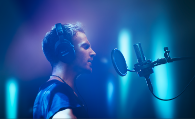  Person, der har Sony-hovedtelefoner på og optager vokaler med C-100-mikrofonen.