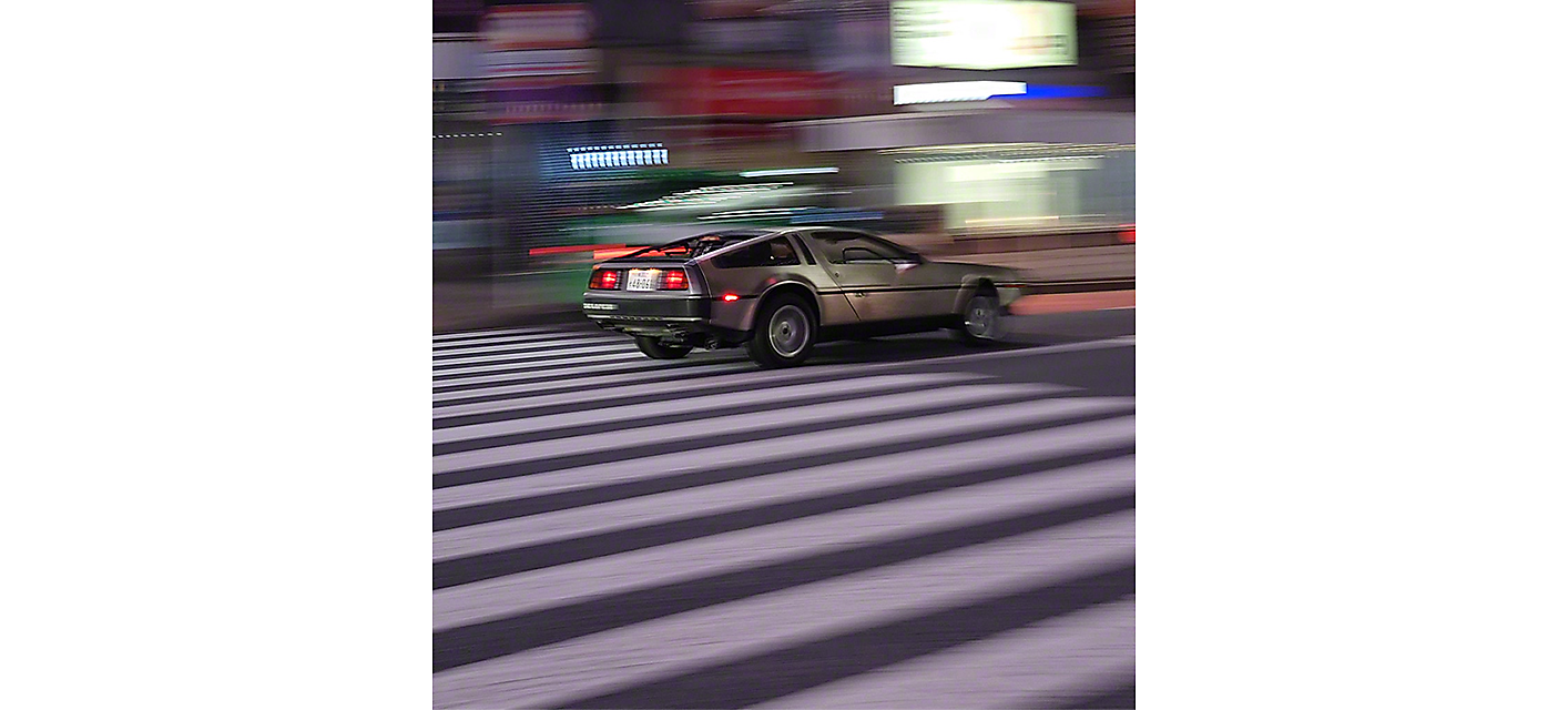 Urheiluauto ajamassa kaupungin läpi, taustalla sumeita valoja