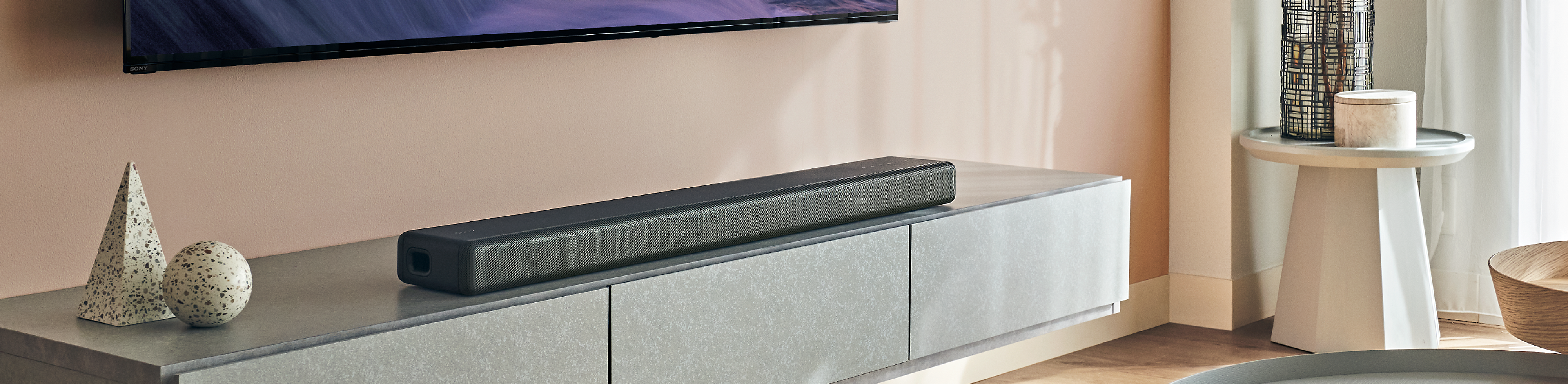 A bright, contemporary living room featuring an HT-A3000 soundbar positioned underneath a wall-mounted BRAVIA TV