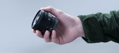 Image of a person holding the E PZ 10-20mm F4 G, showing that the lens is small enough to fit in their hand