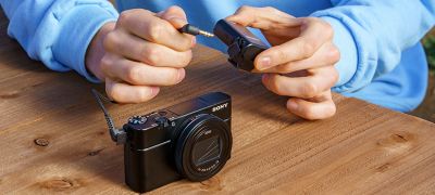En person som kobler ECM-W2BT til et kompatibelt kamera via en 3,5 mm stereominikontakt