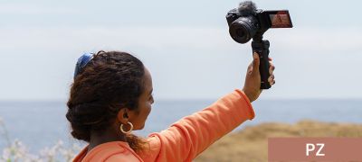 Image of a woman shooting a vlog while operating the zoom control with a grip
