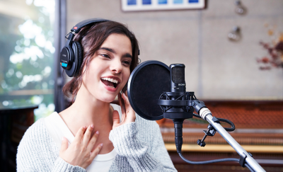 A person wearing Sony MDR-7506 headphone singing in front of a studio microphone