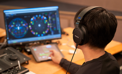 Image of a person wearing Sony MDR-MV1 Headphone doing music editing in front of a desk full of editing equiements