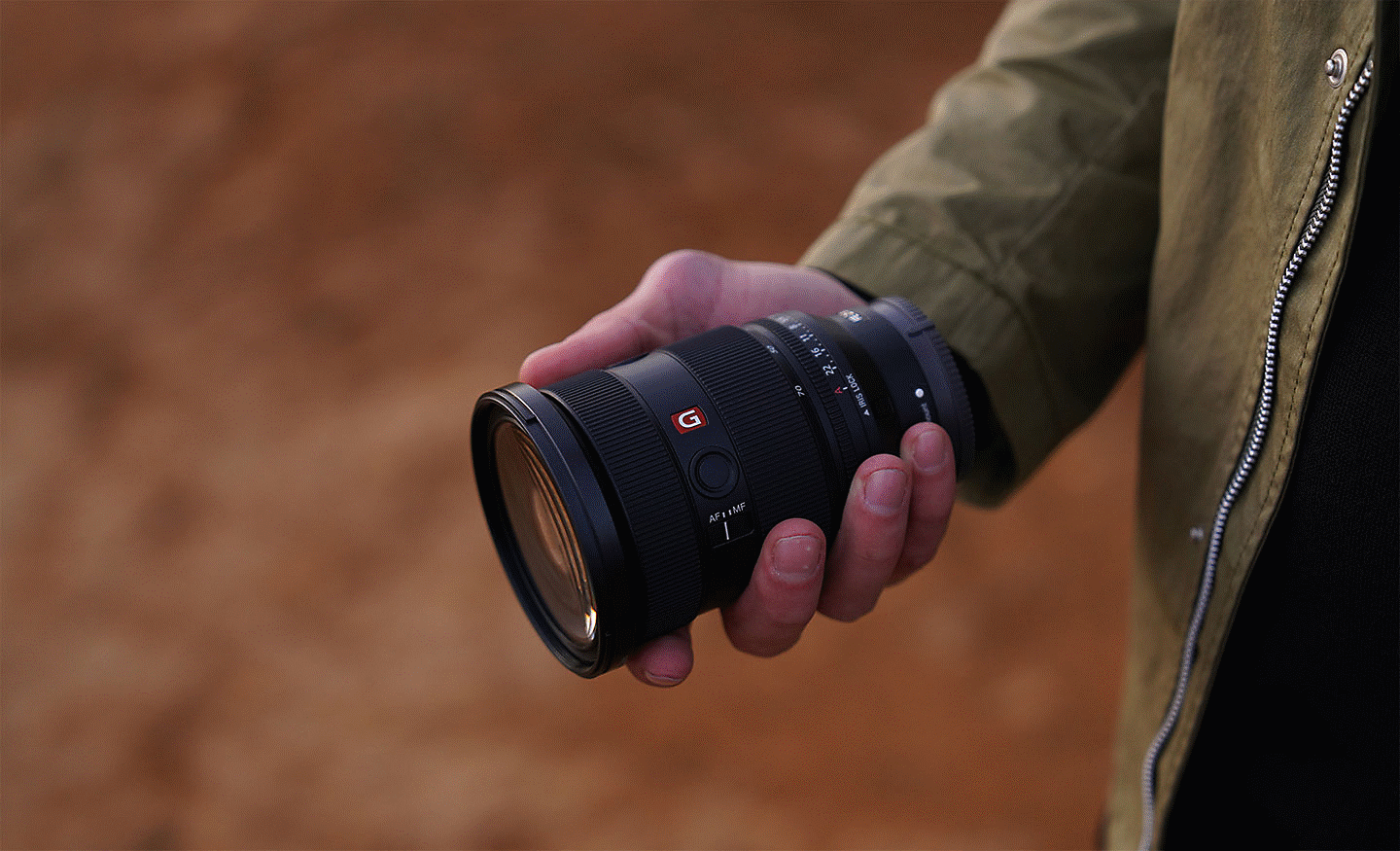 Obrázok objektívu SEL2470GM2 držaného v pravej ruke