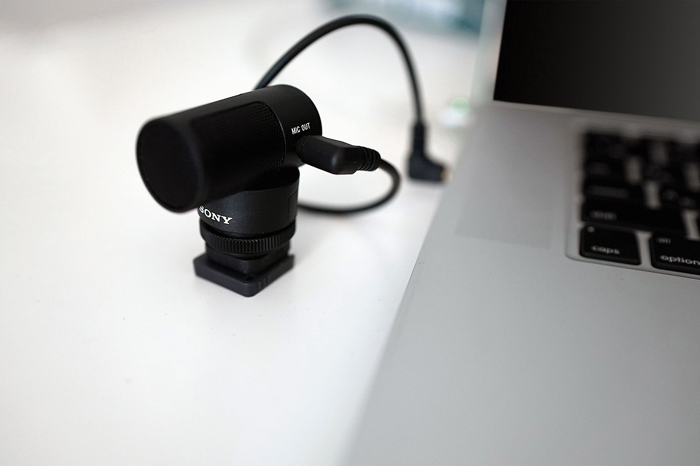 Fotografia mikrofónu ECM-G1 pripojeného k smartfónu pomocou 3,5 mm výstupného konektora a adaptéra.