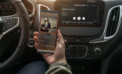 Nuotrauka – XAV-AX4050 prietaisų skydelyje, asmuo srautu perduoda į jį muziką iš savo telefono.