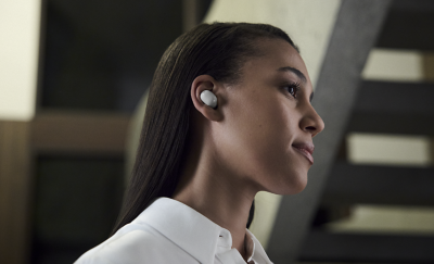 Et profilbilde av en kvinne med en hvit ørepropp og en hvit topp i en moderne bygning.