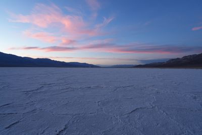 Wide-angle shot of desert landscape with sunset behind distant mountains